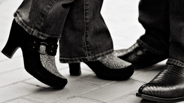 Official Kat Bastion Media Photo with Kat in black suede and faux-hair leopard print mules standing with Stone in black lizard skin cowboy boots